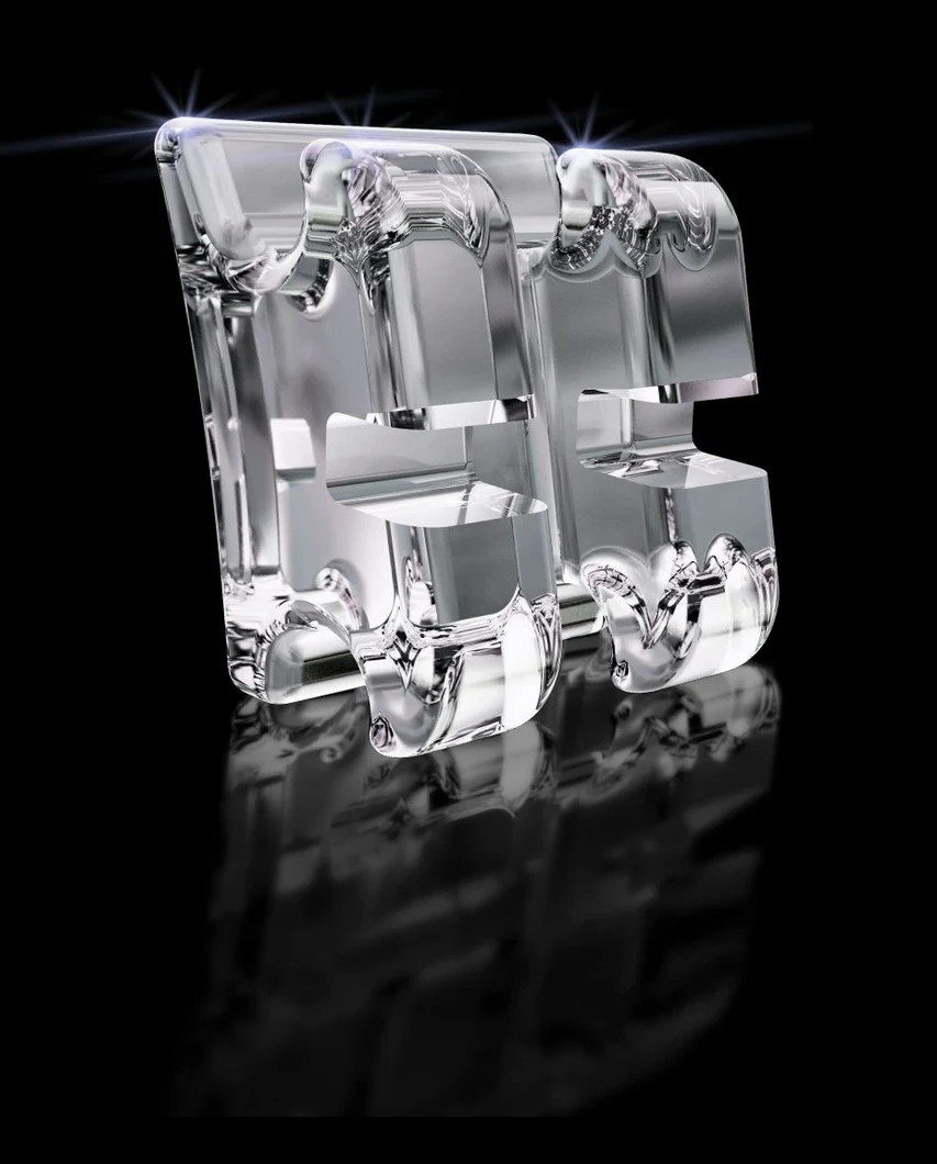 A single ceramic orthodontic bracket, clear and tooth-coloured, lit against black